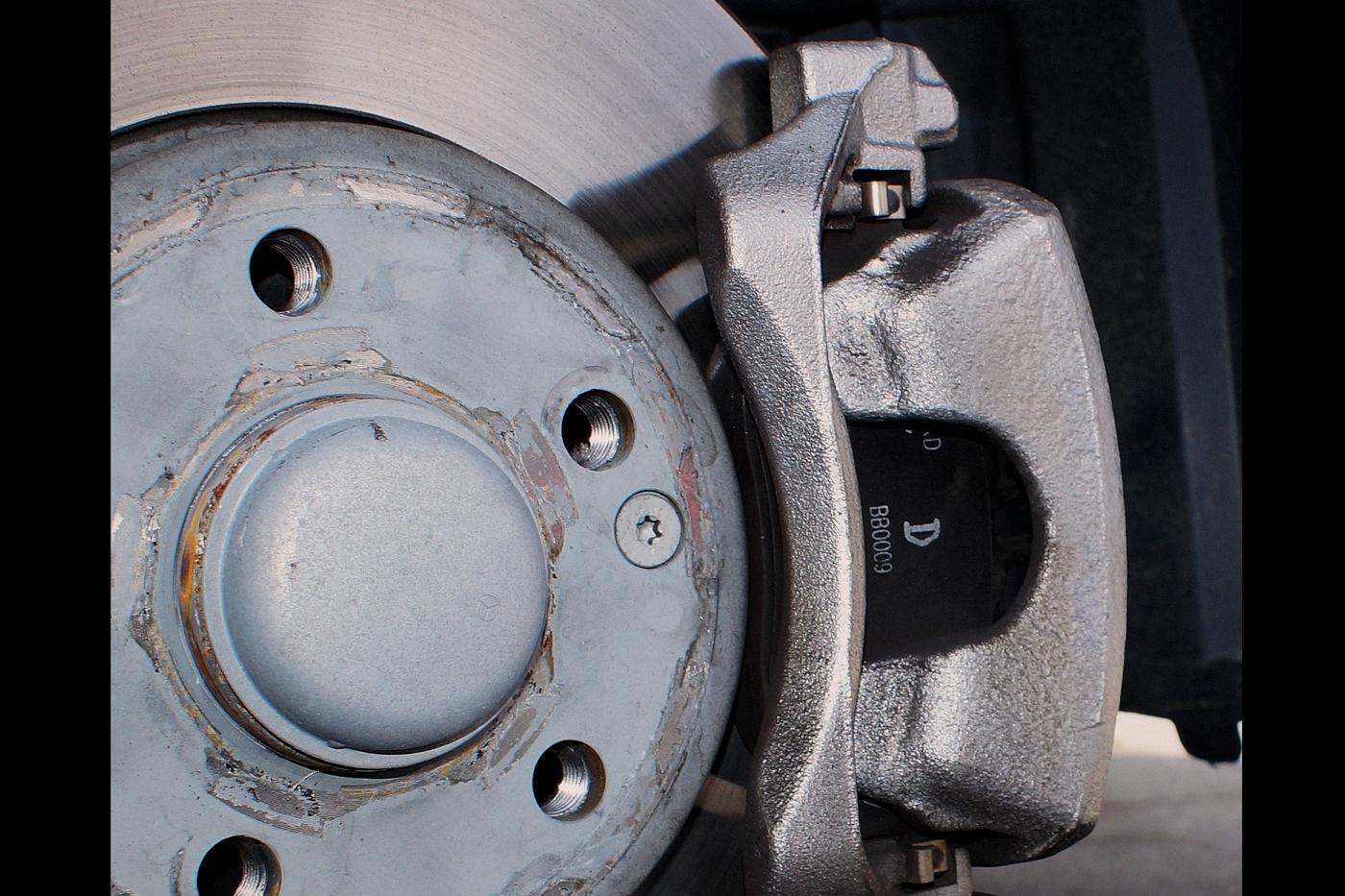 Front brake rotor and caliper with the wheel removed during brake service at Llantera Del Norte INC, 606 Peoria St, Aurora, Colorado, showing the brake pad and rotor surface during inspection / Disco y mordaza de freno delantero con la rueda quitada durante el servicio de frenos en Llantera Del Norte INC, 606 de Peoria St, Aurora, Colorado, mostrando la balata y la superficie del disco durante la revisin