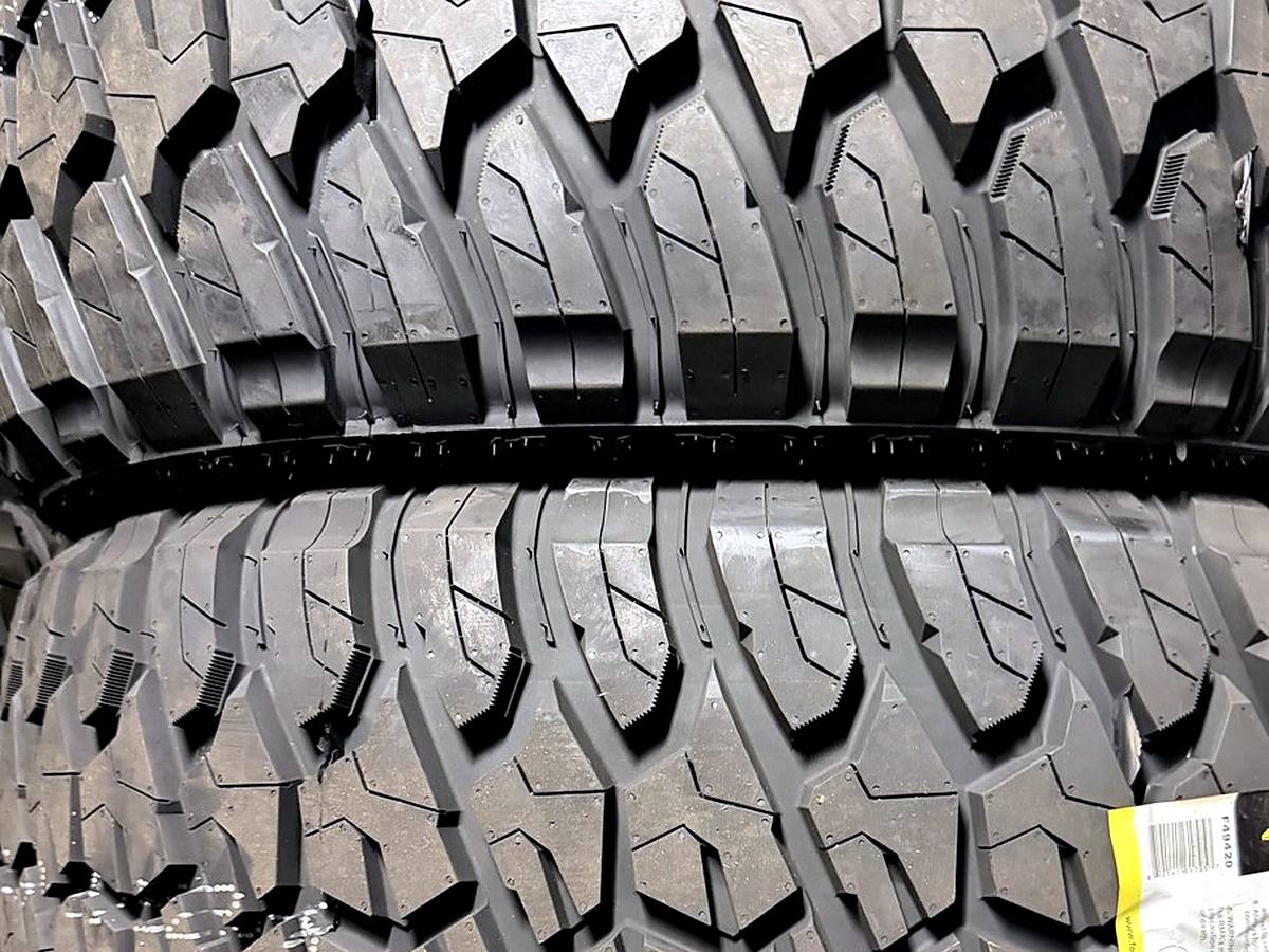 Stack of new mud-terrain truck tires with aggressive tread at Llantera Del Norte INC, 606 Peoria St, Aurora, Colorado / Llantas nuevas de lodo para troca con dibujo agresivo en Llantera Del Norte INC en Aurora, Colorado